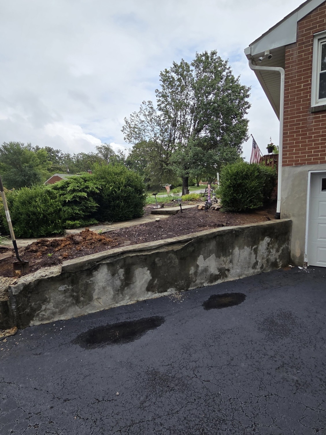 Failing molded concrete retaining wall with cracked, flaking stucco alongside a driveway in Roanoke, VA